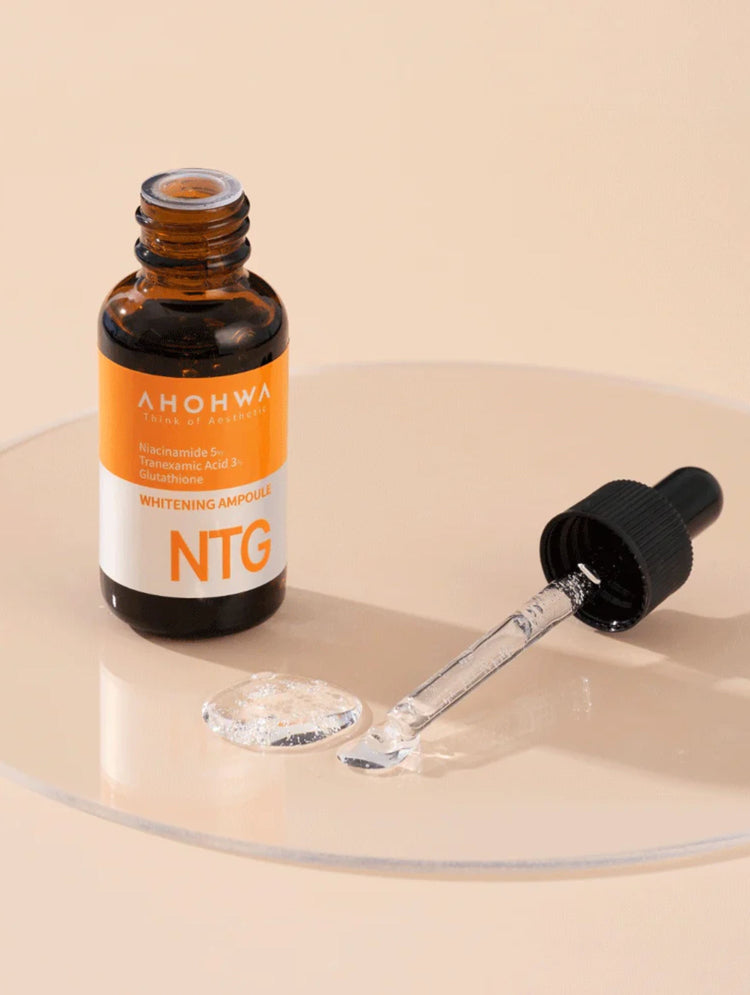 A bottle of Ahohwa NTG Whitening Ampoule with a dropper on a beige background